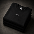Stack of black sweatshirts with 'BMBK' branding on a dark surface